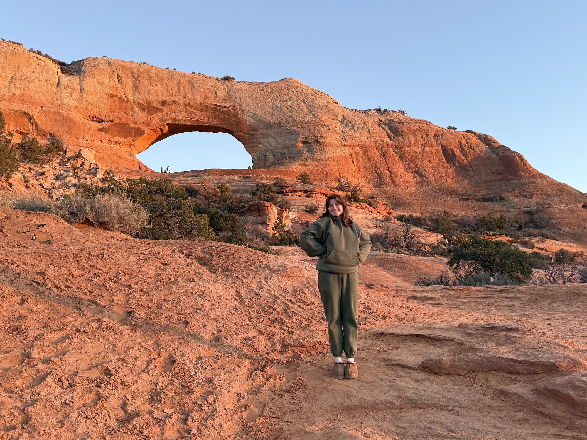 Nora Fortune standing in front of a red rock arch at sunset